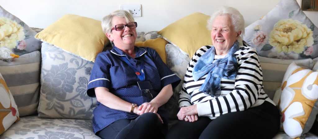Carer and Resident laughing together on a sofa