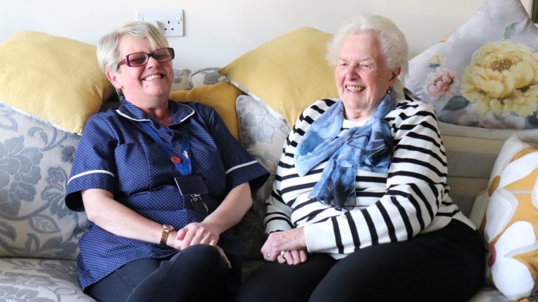 Resident and Carer laughing on sofa