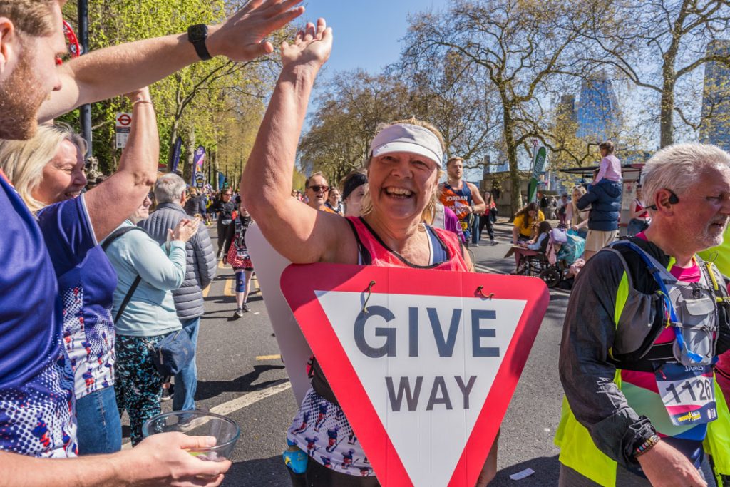 RBVE runner with a give way sign strapped to her, high fiving cheer station