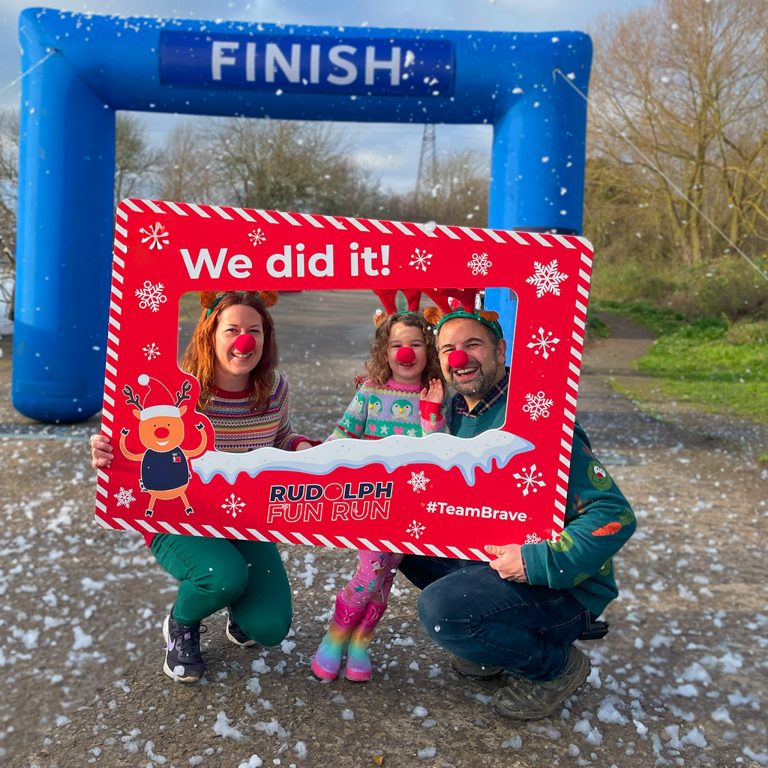 Family smiling at the finish line of the Rudolph Fun Run