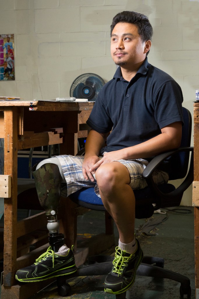 Gurkha veteran sitting on desk chair at work bench