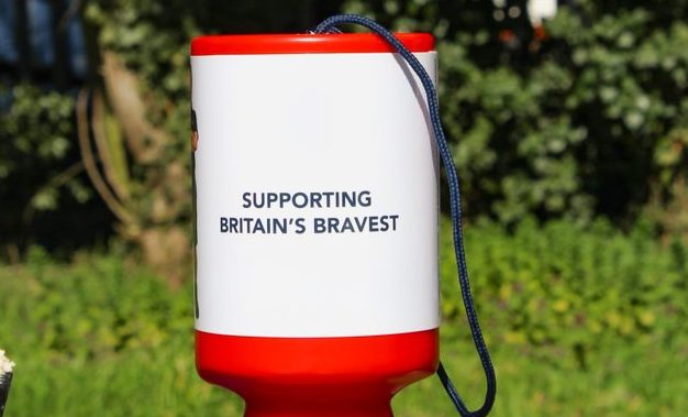 One pound being dropped into a red and white collection pot