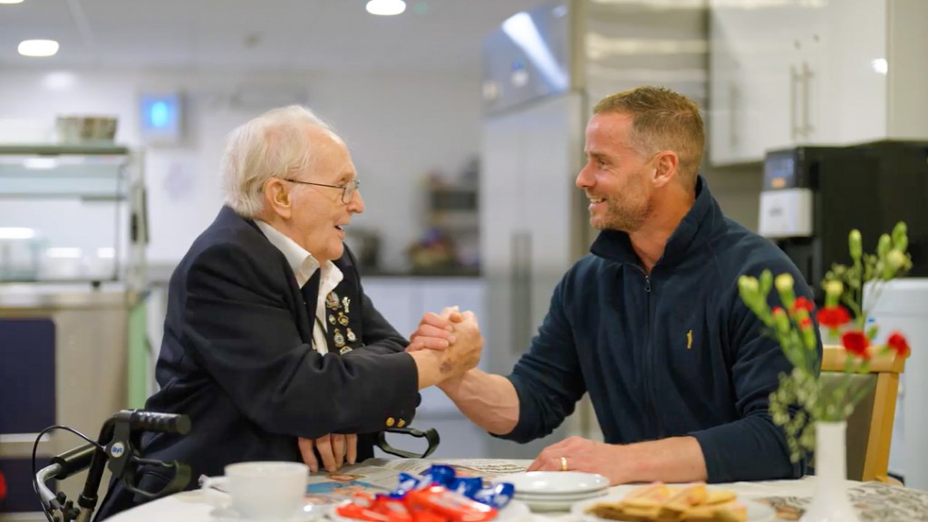 Two veterans from different generations shake hands with a smile