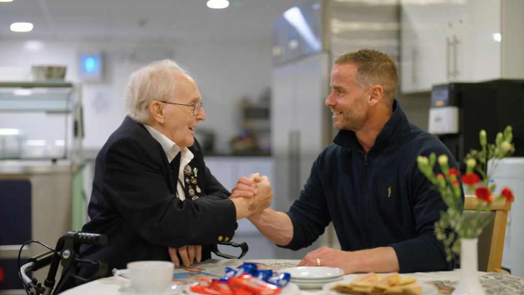 Two veterans from different generations shake hands with a smile