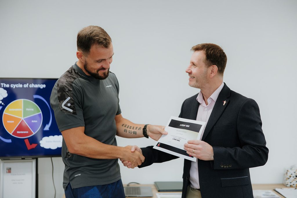 Two men shaking hands after being handed Lifeworks award
