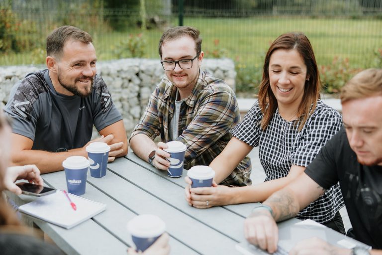 RBVE Lifeworks participants talking and laughing with a coffee on an outdoor bench