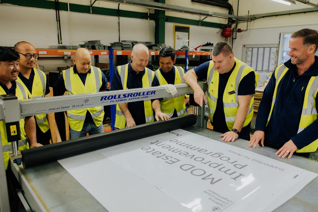 Our social enterprise BBMC Team standing behind a sign making machine for a team photo