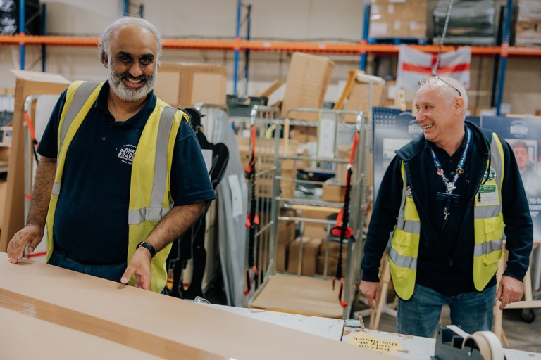 Two social enterprise workers smiling creating boxes for delivery